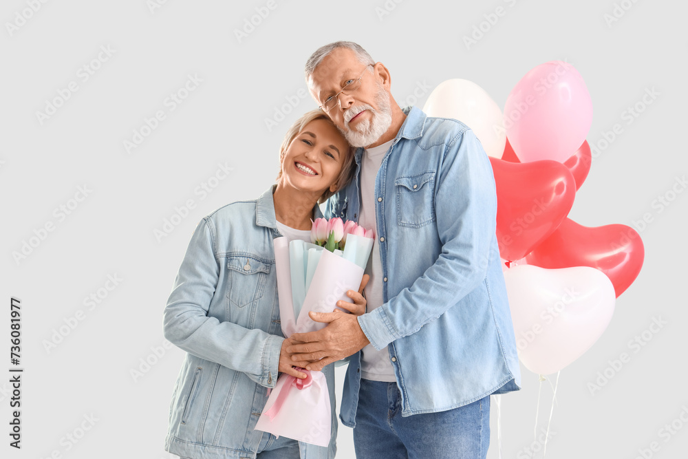Mature couple with tulips hugging on light background. Valentine's Day celebration