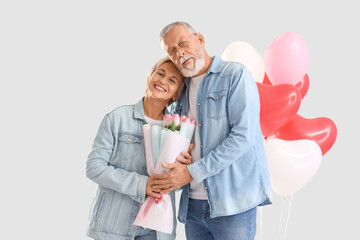 Poster - Mature couple with tulips hugging on light background. Valentine's Day celebration