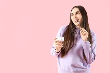 Poster - Thoughtful young woman with tasty yoghurt on pink background