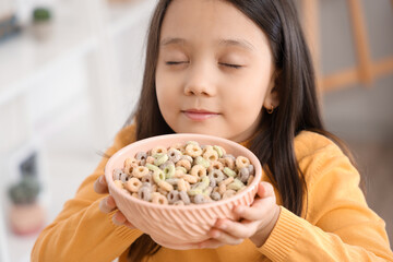 Canvas Print - Cute little girl with bowl of cereal rings in kitchen, closeup