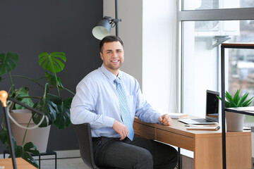 Canvas Print - Young businessman sitting at table in office