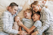 Parents and three children lie on the bed and bonding. Family happiness, time together between mom and dad with children.