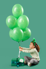 Poster - Cute little girl with leprechaun's hat, gift box and balloons on green background. St. Patrick's Day celebration