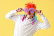 Businessman in funny disguise on yellow background. April Fools' Day celebration