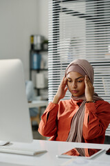 Aufkleber - Young tired female manager touching her head while sitting by workplace with desktop computer and suffering from headache
