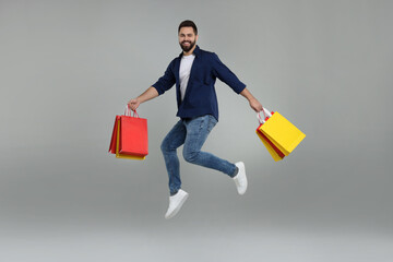 Sticker - Happy man with many paper shopping bags jumping on grey background