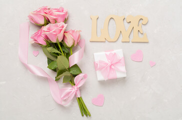 Wall Mural - Pink roses with hearts and gift box on concrete background, top view. Valentines day concept