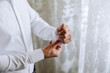 © Vasil - handsome business man buttoning shirt sleeves at home. The groom is preparing for the wedding. Close-up photo.