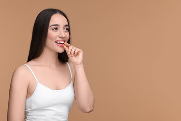 Poster - Beautiful young woman with vitamin pill on beige background. Space for text