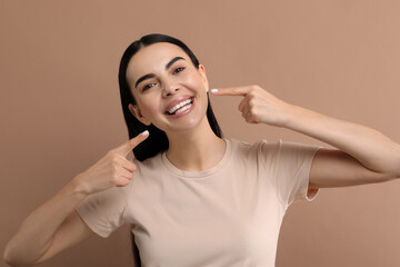 Wall Mural - Beautiful woman showing her clean teeth and smiling on beige background