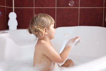 Wall Mural - Little girl having fun in bathtub at home