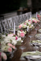 Wall Mural - A large, long, decorated, wooden table and chairs, covered with a white tablecloth with dishes, flowers, candles.