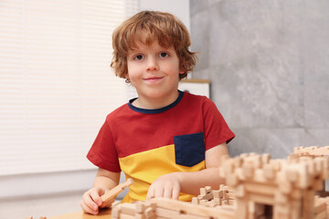 Poster - Little boy playing with wooden entry gate at table in room. Child's toy