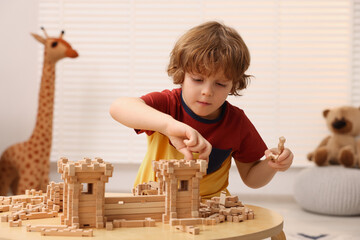 Wall Mural - Little boy playing with wooden entry gate at table in room. Child's toy