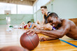 © Marko Geber - Young people taking a break from playing basketball in an indoor basketball gym
