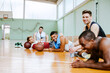 © Marko Geber - Young people taking a break from playing basketball in an indoor basketball gym