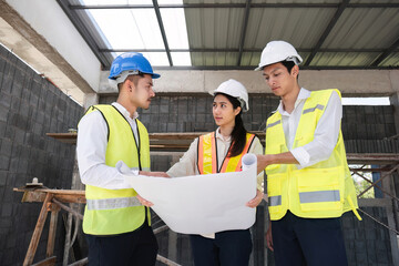 Wall Mural - Team of professional civil engineers and architects holding project plan paper, supervising and controlling construction project work at construction site.