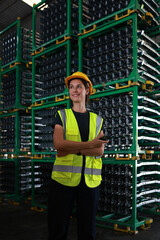 At the raw material storage in the warehouse distribution, there is a portrait of a young woman wearing a green safety reflector vest, who is ready to supply materials to the production line.