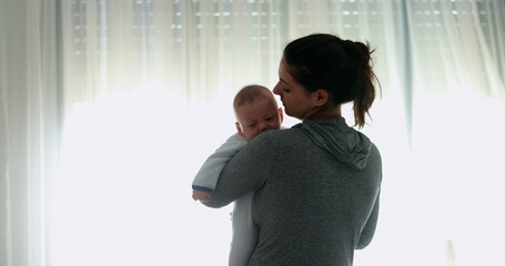 Wall Mural - Revealing Candid mother holding and consoling crying baby good for transition