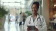 © MP Studio - smiling female healthcare professional, stands in a hospital corridor holding a tablet