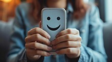 Close-up of hands holding a smartphone with a happy face emoji on the screen, symbolizing positive digital communication.