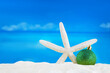 Shiny green ball with starfish on sand of beach. Christmas, New Year. Copy space