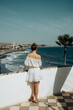 Kobieta w białej sukience stoi tyłem i patrzy na plażę i ocean, Gran Canaria, Hiszpania