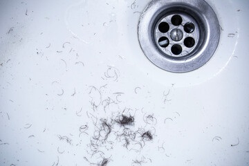 shaved hair from the intimate areas of the pubic area after shaving and depilation remaining on the walls of the bathroom sink, close-up texture