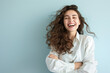 Copy space of a young entrepreneurial businesswoman, smiling and cheerful against a light blue background, white shirt, and tousled hair