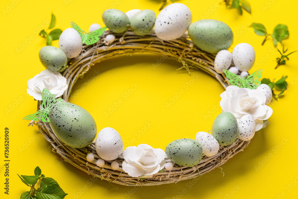 Easter wreath with flowers, eggs and butterflies on yellow background