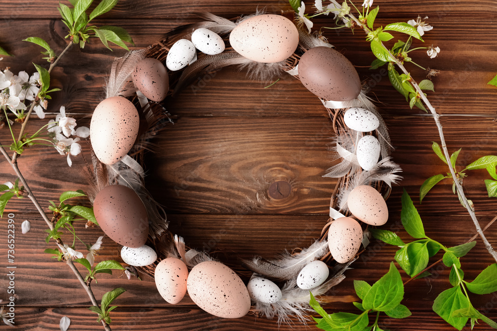 Easter wreath made of eggs and feathers with branches on brown wooden background