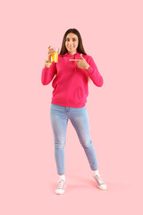 Sticker - Young woman pointing at glass of juice on pink background