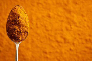 Wall Mural - Turmeric root powder on a spoon on an empty background with copy space