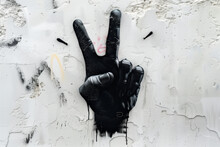 Grunge Graffiti On A Wall With Two Fingers Painted In Black. Spray Painted Graffiti Of Hand Gesture V Sign For Victory