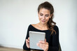 © muse studio - Concentrated young woman browsing on a tablet, engaged in digital communication.