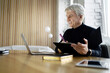 © muse studio - Smiling senior professional using a digital tablet in a modern office setting.