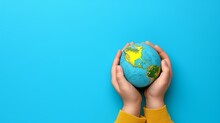 Caring Hands Cradle A Miniature Earth On Blue Background, Symbolizing Responsibility For Our Planet.