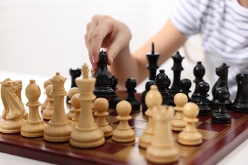 Wall Mural - Little child playing chess at table indoors, closeup