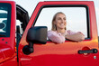 © Wavebreak Media - Young Caucasian woman enjoys a drive in a red vehicle on a road trip