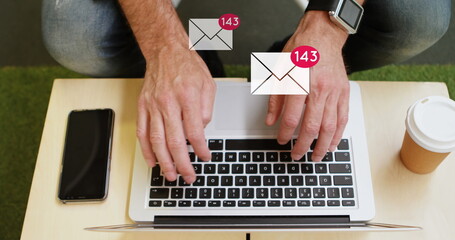 Poster - Digital composite of a man typing on his laptop on a desk with email icons increasing in count in th