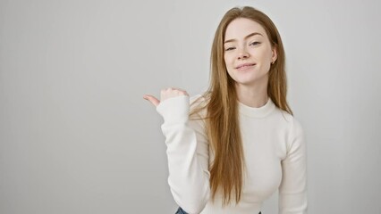 Canvas Print - Young blonde woman wearing sweater standing pointing thumb up to the side smiling happy with open mouth over isolated white background