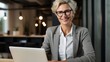 © Naknakhone - Happy cheerful mid aged business woman executive in office using laptop at work, smiling professional mature 40 years old female company manager working on computer.