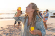 Young Caucasian woman enjoys blowing bubbles on the beach at sunset
