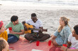 © wavebreak3 - Diverse friends enjoy a beach gathering, having a party, with copy space