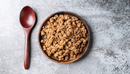 Wall Mural - Top view of dried soy bean meat mince on a plate with wooden spoon, on grey table