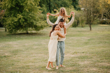 Summer shot of a wonderful happy family spending quality time together in park. Mother, father and their daughter.