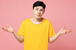 Young sad Caucasian man he wears yellow t-shirt casual clothes spread hands shrugging shoulders looking puzzled, have no idea isolated on plain pastel light pink background studio. Lifestyle concept.