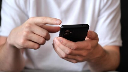 man scrolling his smartphone. cropped frame to focus on hands and smartphone.