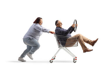 Poster - Woman pushing a mature man with a steering wheel inside a shopping cart