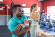 © Wavebreak Media - Fit African American man and young Caucasian woman stretching at the gym